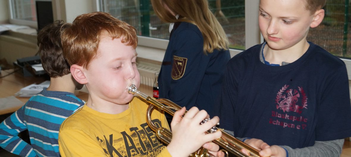 Ein Junge zeigt einem anderen Jungen das Spielen einer Trompete.