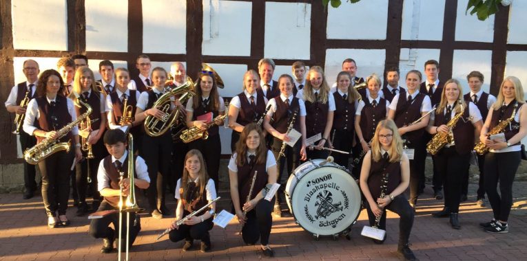 Eine Musikkapelle posiert vor einem alten Haus.