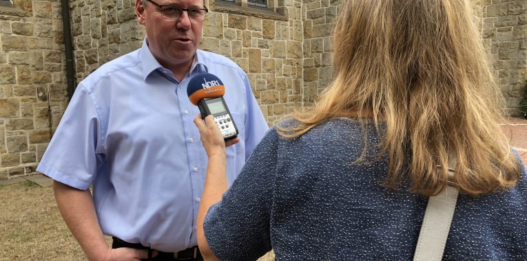 Eine Journalistin interviewt den Vorsitzenden der Blaskapelle.